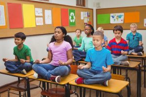 Pupils meditating on classroom desks at the elementary school